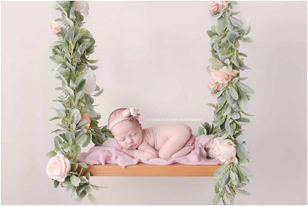 newborn baby girl laying on floral wooden swing