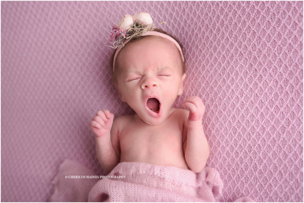 newborn portrait session in new orleans, louisiana with cherilyn haines photography; 1 month old baby girl laying on pink blanket yawning