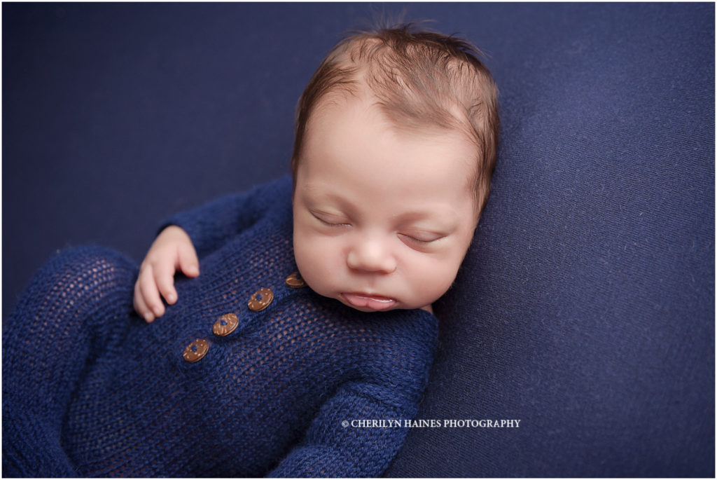 26 day old newborn baby boy photographed by Cherilyn Haines Photography in Baton Rouge, Louisiana; baby wearing navy blue footed pajamas