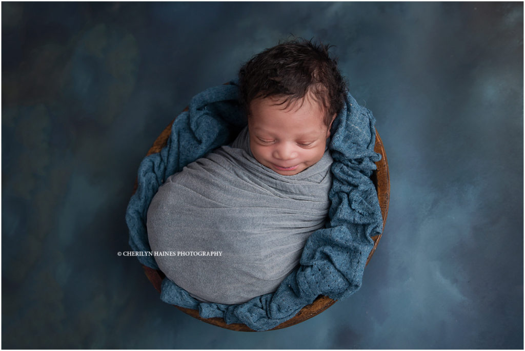 12 day old baby boy photographed swaddled in bowl on dark teal backdrop