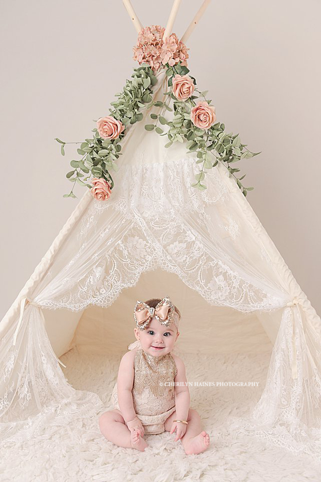 6 month portraits photographed by cherilyn haines photography in baton rouge, louisiana; 6 month old baby girl sitting in front of lace teepee with pink flowers