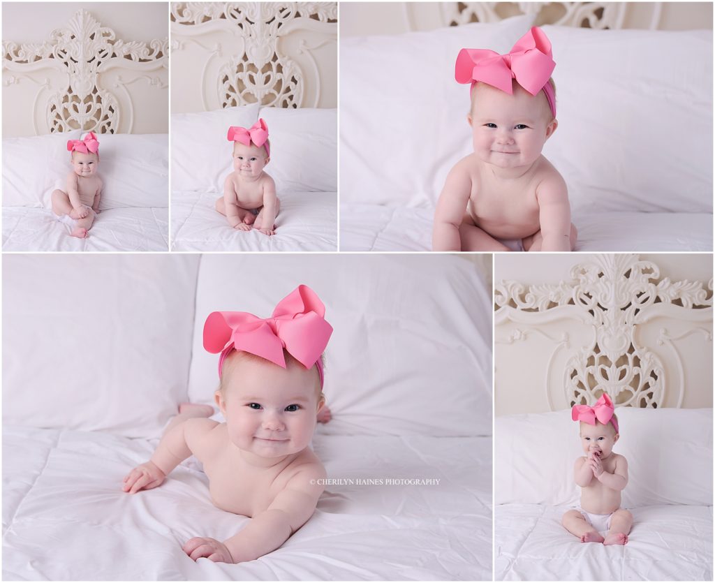 6 month old baby girl photographed laying on a white bed with ornate headboard