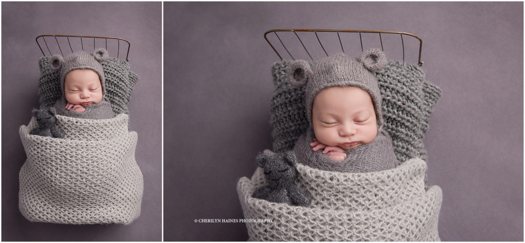 newborn session with baby boy wearing a gray teddy bear hat laying in a tiny antique doll bed with a tiny teddy bear