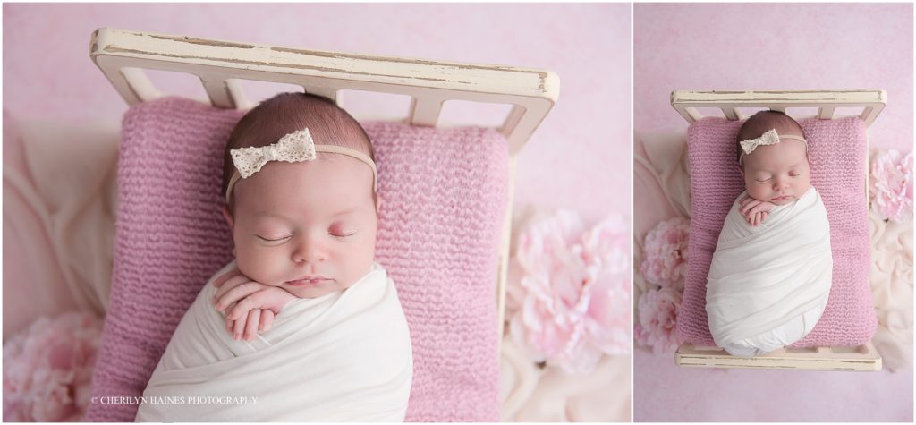 newborn photographers in louisiana; baby girl laying in tiny wooden bed with pink blanket