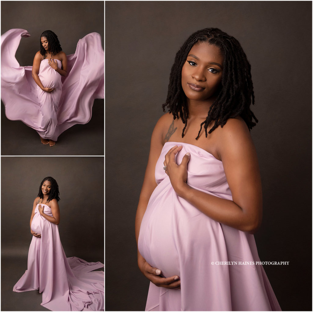 pregnant woman photographed in light pink flowing fabric on gray backdrop