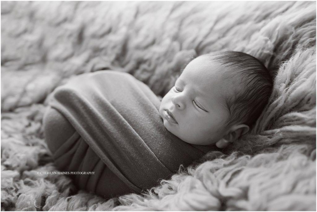 black and white portrait of 3 week old baby boy swaddled and laying on fuzzy rug